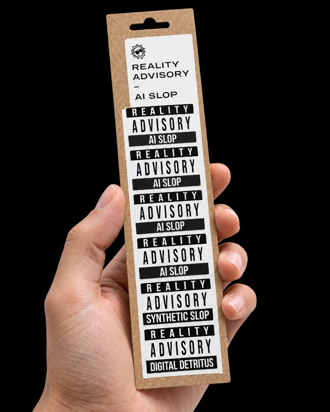 A hand holding the Reality Advisory pack of six black-and-white warning stickers on recycled cardboard.