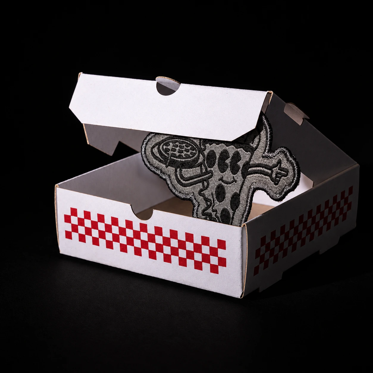The opened Slice mini pizza box with a black-and-white embroidered Homeslice pizza character inside.